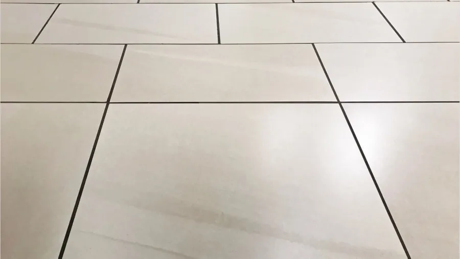 Off-white tile floor with dark grout lines, perspective view.