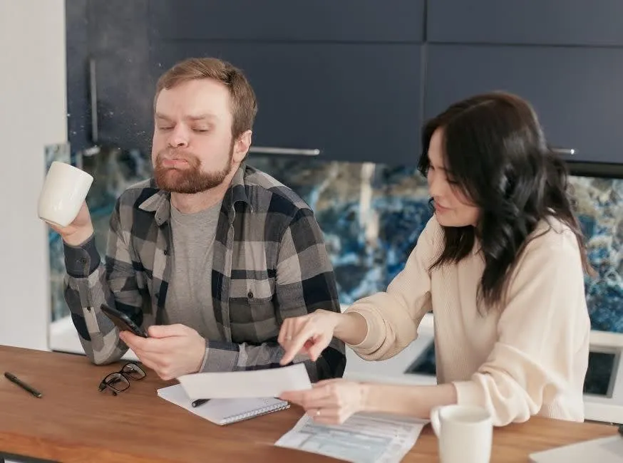 Kitchen fitting quote and paperwork on a table while a Bath homeowner works out a deposit