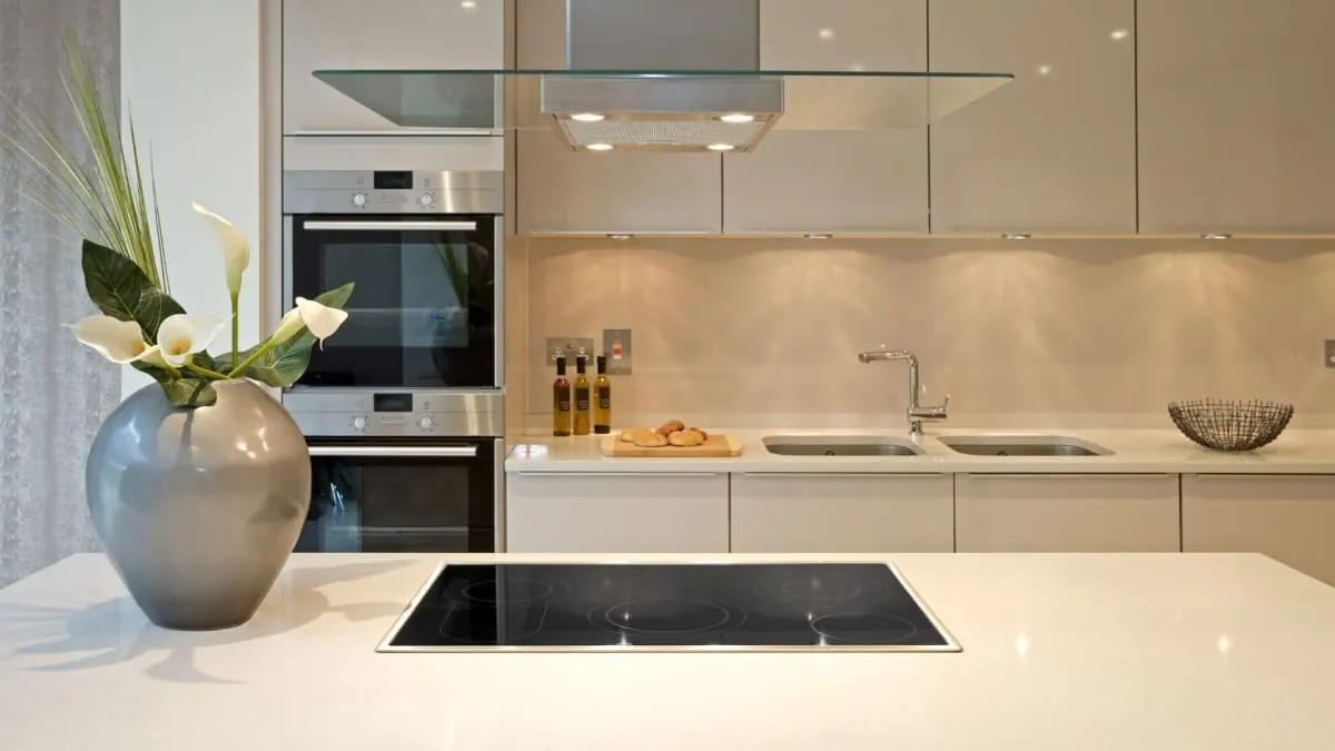 Modern white kitchen with island and flowers. Stainless steel appliances and cabinets.