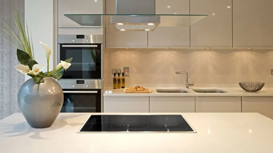 Modern white kitchen with island and flowers. Stainless steel appliances and cabinets.