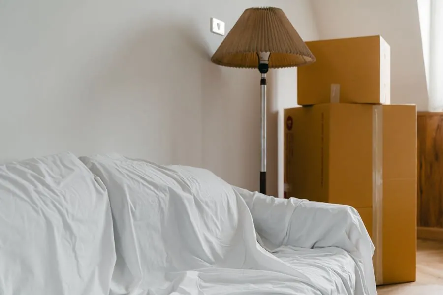 Furniture covered with dust sheets and boxes stacked in a room during a Bath home renovation