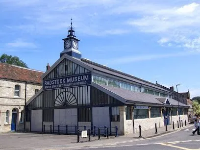 Radstock Museum building exterior with clock tower, blue sky, and street scene.