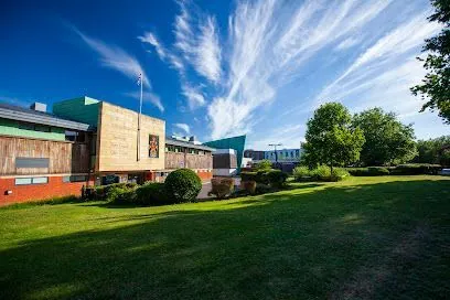 Exterior of a modern building with green lawn, blue sky, and wispy clouds.
